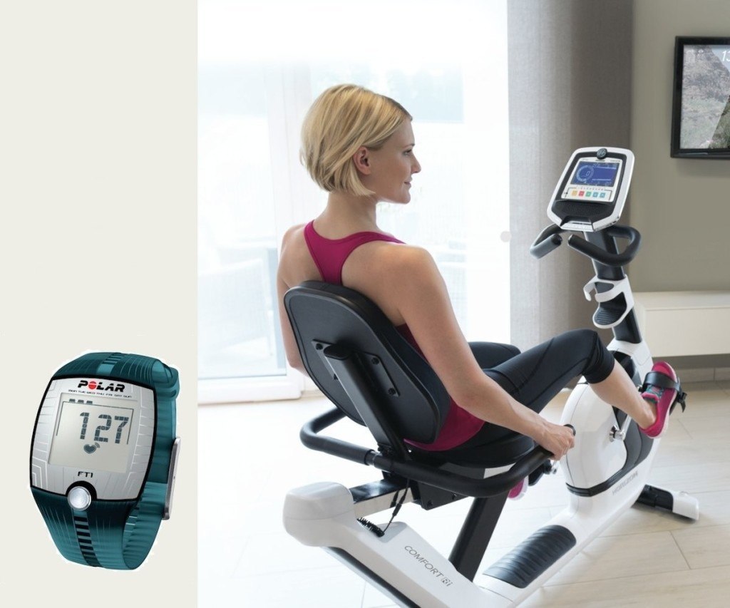 Frau trainiert auf einem Ergometer mit Darstellung einer Pulsuhr