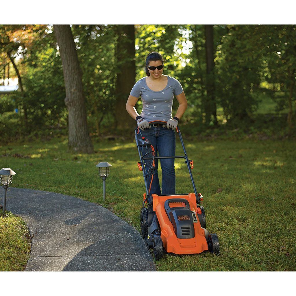 Frau mit einem Elektro Rasenmäher von Black und Decker bei der Gartenarbeit