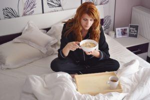 Frau frühstückt im Bett im Aldi Bettdecken Test